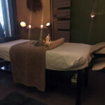 Salle de massage chez EMPAB, décorée dans des tons verts et naturels, équipée d'une table de massage, de lumières tamisées, de bougies et d'éléments de décoration propices à la détente.