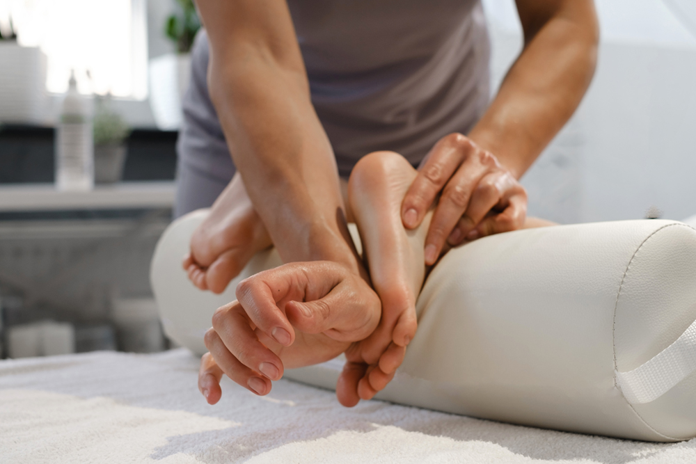 Massage des jambes d’un jeune par un praticien professionnel, dans un cadre apaisant et bienveillant.