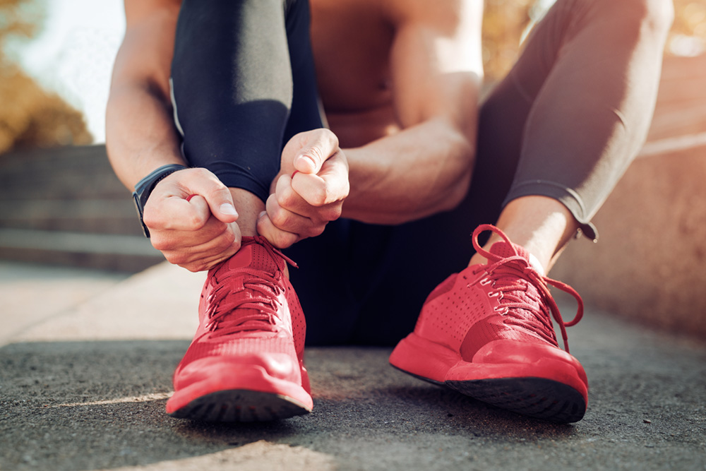 Un sportif en train de lacer ses chaussures, illustrant l’importance de la détente et de la conscience corporelle, notamment grâce au massage du périnée masculin proposé par EMPAB.