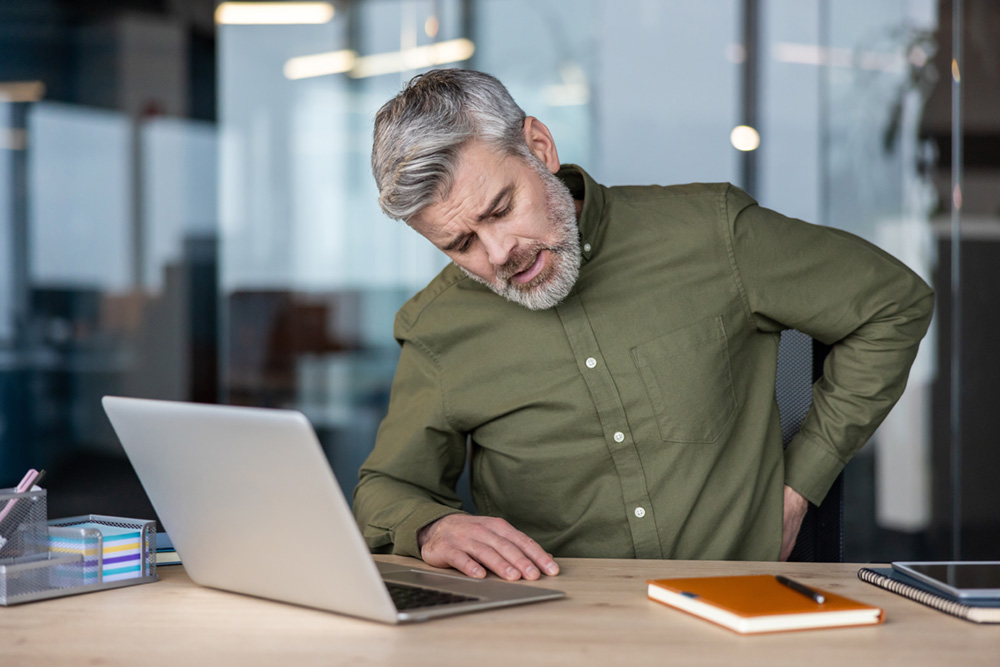 Un homme sédentaire au travail, illustrant l’importance de la détente et du massage du périnée masculin EMPAB pour améliorer le confort et la circulation sanguine au quotidien.
